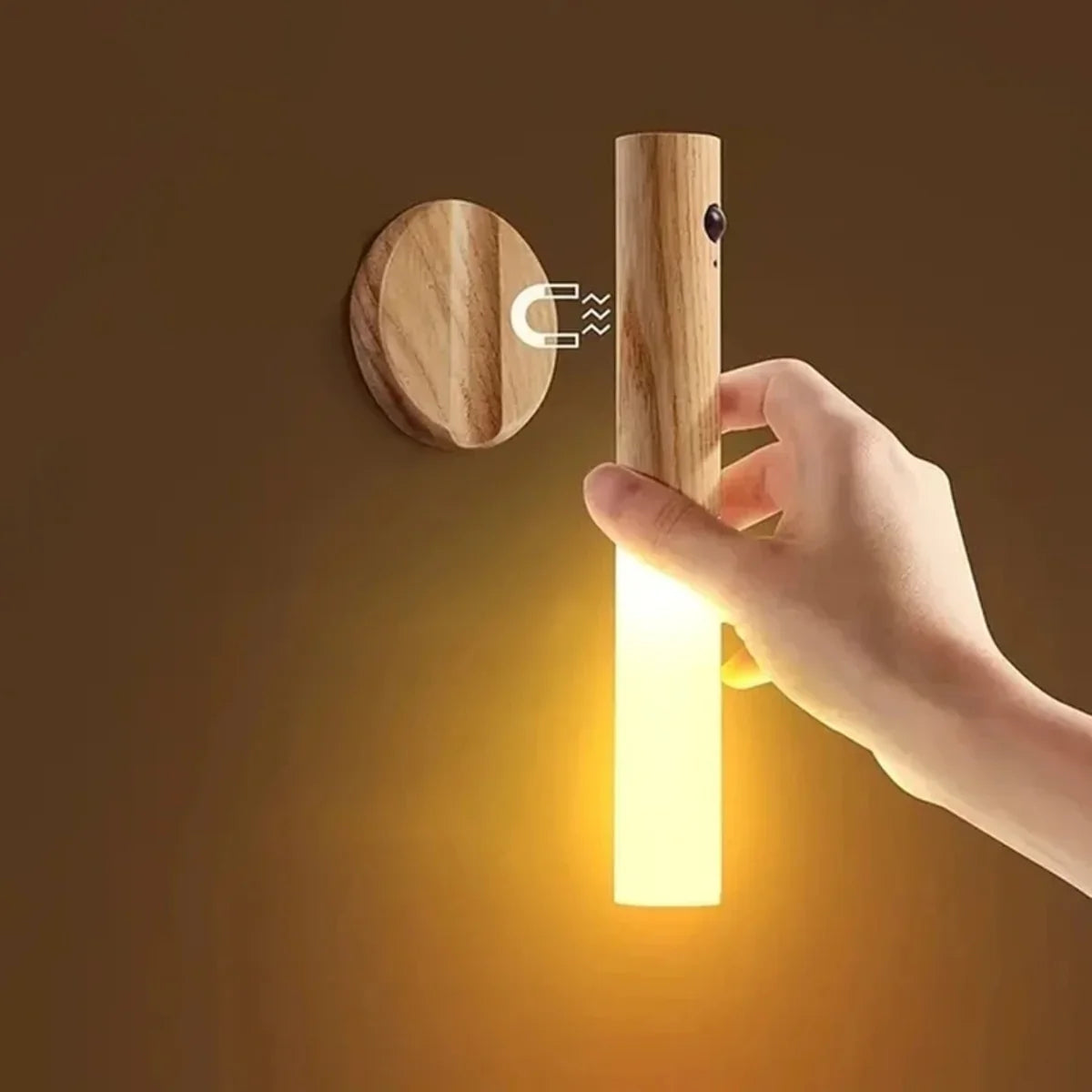 Hand holding warm glow wooden LED night light with magnetic wall mount, modern home lighting solution